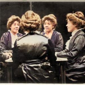 Multigraph photographic portrait of Emma Ransom, Britt Ransom’s great-great grandmother. Four versions of Emma sit around a table, one in profile, one whose back is to the viewer, and two who face the viewer with their gazes focused to the right and left respectively. Emma wears brown hair in an updo and a purplish gray dress with white ruffles on the front.